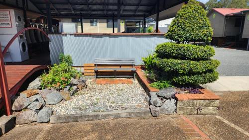 a bench in a garden with rocks and trees at T's Resort & Motel in Port Macquarie