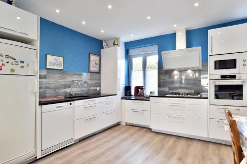 - une cuisine avec des appareils électroménagers blancs et des murs bleus dans l'établissement La Saudrais - Parking - Jardin, à Dinard
