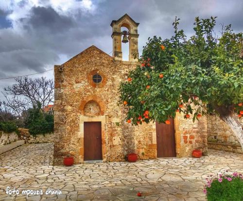 an old stone church with an orange tree in front at Angela Home, 5Street, Perivolia in Perivólia
