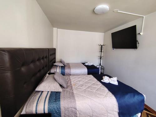 a bedroom with two beds and a flat screen tv at Hostal San Antonio Inn in Puno