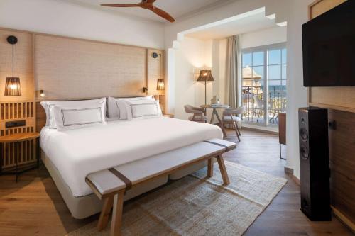 a bedroom with a large white bed and a table at Meliá Isla Canela in Isla Canela