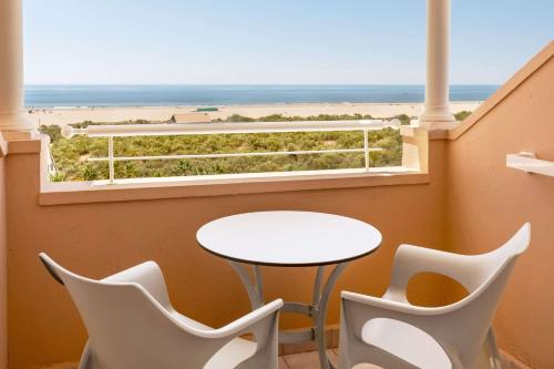 a table and chairs in a balcony with a view of the ocean at Meliá Isla Canela in Isla Canela