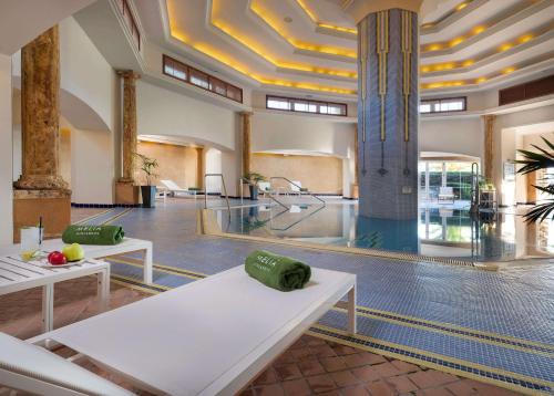 a lobby with benches and a pool in a building at Meliá Isla Canela in Isla Canela