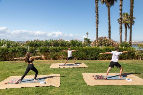 a group of people doing yoga in the grass at Meliá Isla Canela in Isla Canela