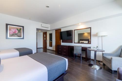 a hotel room with a bed and a desk and a couch at Ejecutivo Express Guadalajara Providencia - Av México in Guadalajara