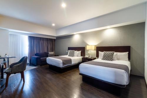 a hotel room with two beds and a couch at Ejecutivo Express Guadalajara Providencia - Av México in Guadalajara