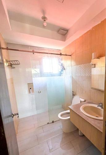 a bathroom with a shower and a toilet and a sink at JResidences - 5 Bedrooms Cozy Home in Bacolod