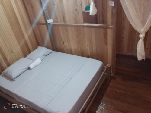 a bed in a room with a wooden wall at Posada Brisas del Cachcal in Panguí