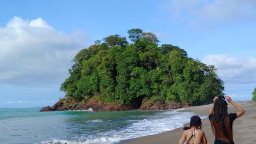 two women standing on the beach looking at an island at Posada Brisas del Cachcal in Panguí