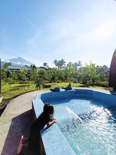 a person laying on a bench next to a swimming pool at Raturinjani homestay in Selong
