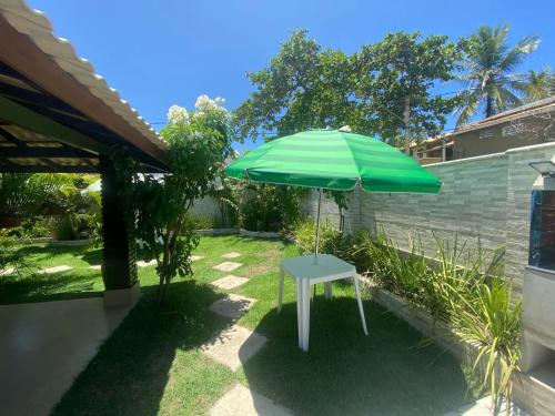 a green umbrella sitting in a yard at Casa poucos passos do mar em Buraco da Velha in Lauro de Freitas