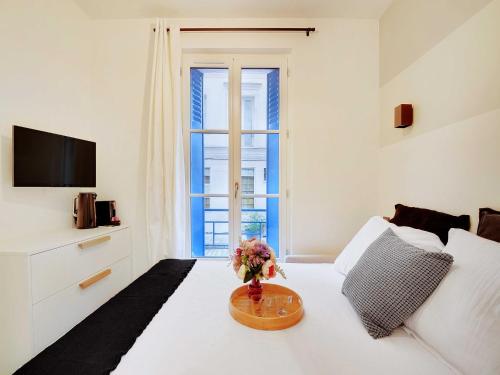 une chambre avec un lit blanc avec un vase de fleurs sur une table dans l'établissement Classy studio- Gare de Lyon Bastille, à Paris