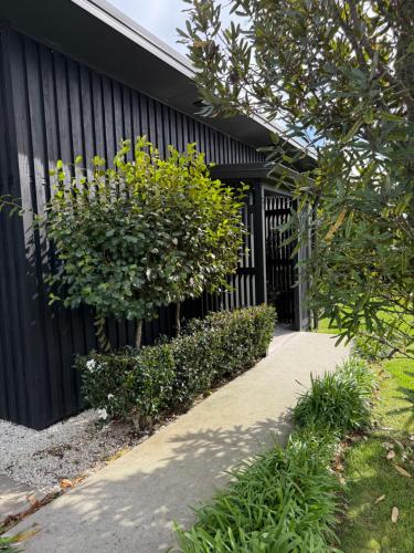 a sidewalk next to a black fence with a bush at The Gate House in Tauranga