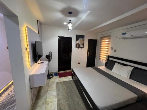 a bedroom with a bed and a desk and a television at Konar-Apts, Cozy Room with private kitchen, City view Balcony, 24hrs power, Security, Wifi, Gwarinpa Express by Dawaki Junction in Gwarinpa
