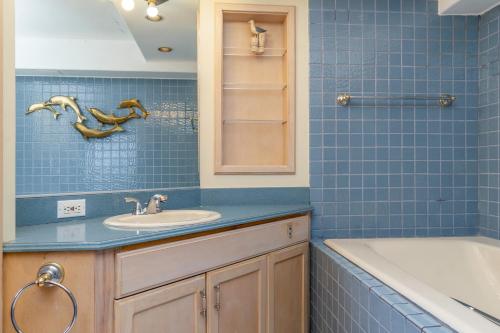 a blue tiled bathroom with a sink and a tub at Hawaiian Monarch Penthouse 402 in Honolulu