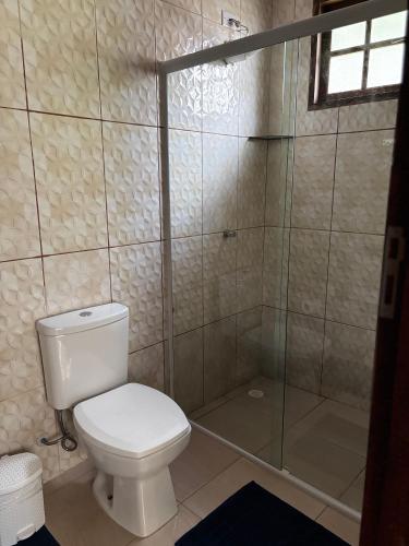 a bathroom with a toilet and a glass shower at Chalé Canoa in Paraty
