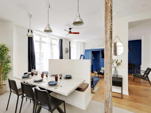 une salle à manger et un salon avec une table et des chaises blanches dans l'établissement Authentic Loft - 2BR 8P - Oberkampf, à Paris