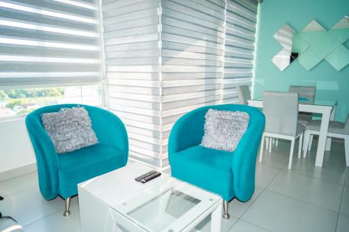 a living room with two blue chairs and a table at Apartamento - Velas al Mar, Santa Marta in Gaira