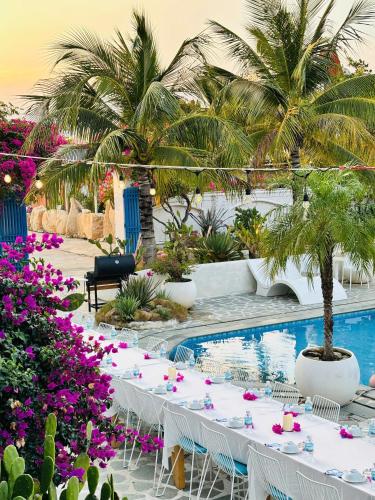 a table with white chairs and flowers next to a swimming pool at Santorini Villa Cam Ranh in Cam Ranh