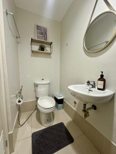 a bathroom with a toilet and a sink and a mirror at 8F Cozy 1-Bedroom Unit The Loop Towers in Cagayan de Oro