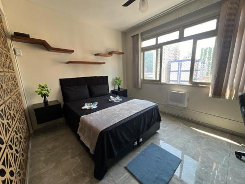 a bedroom with a bed and a large window at Kitnet completa com ar condicionado in São Vicente