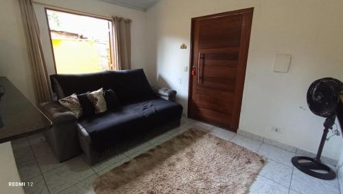 a living room with a black leather couch and a window at Recanto Machado in Paraty