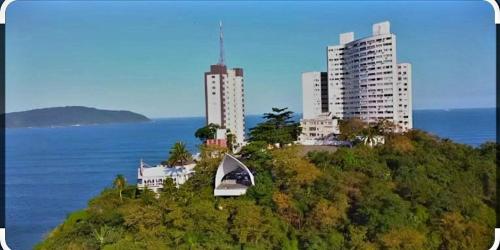 a city on a hill with buildings and the ocean at Kitnet completa com ar condicionado in São Vicente