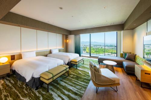 a hotel room with two beds and a couch at Beppu SUGINOI HOTEL in Beppu