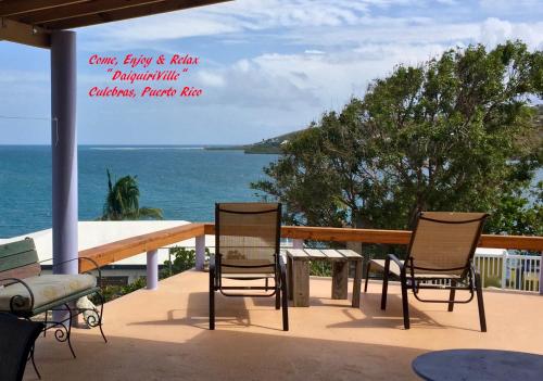a patio with chairs and a table and the ocean at Come, Enjoy & Relax DaiquiriVille on Culebra Island Puerto Rico in Culebra