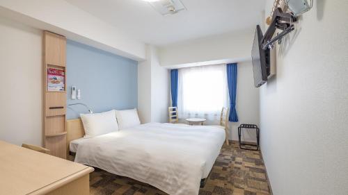 a bedroom with a white bed and a window at Toyoko Inn Kobe Sannomiya Ekimae in Kobe