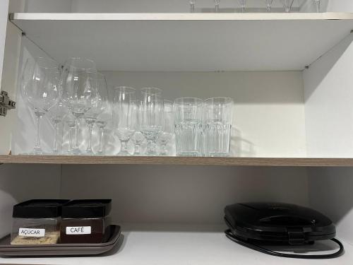 a shelf filled with glasses sitting on top at Apto 2 qtos na quadra da praia Itaparica in Itaparica