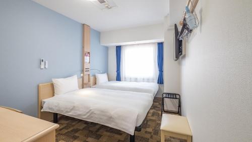 a room with two beds and a window at Toyoko Inn Kobe Sannomiya Ekimae in Kobe