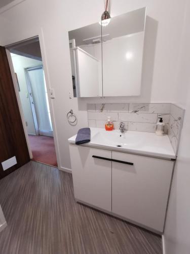 a white kitchen with a sink and a mirror at Spacious 2 bedroom apartment in Whangarei