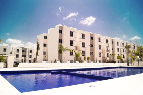 a large apartment building with a swimming pool in front of it at Departamento en Aldea Tulum in Tulum