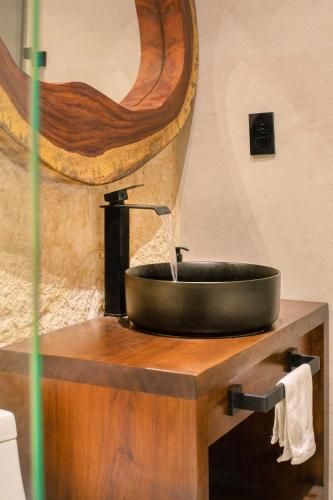 a black sink on a wooden counter with a mirror at Departamento en Aldea Tulum in Tulum