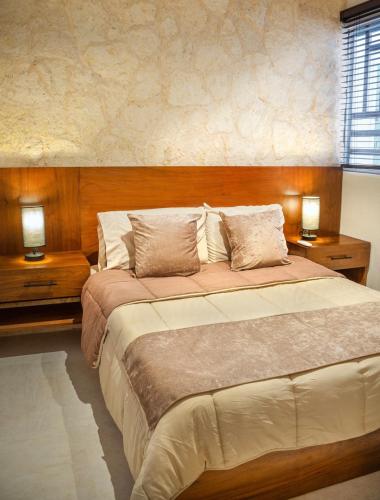 a bedroom with a large bed with two night stands at Departamento en Aldea Tulum in Tulum