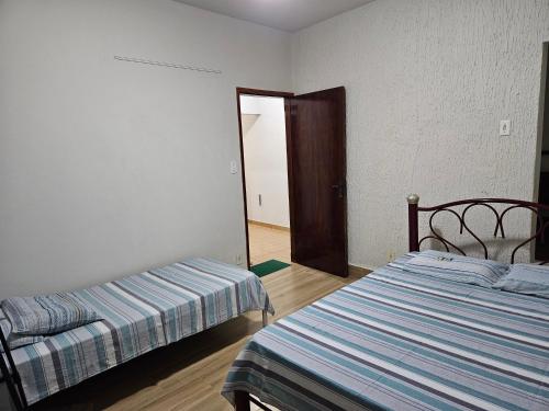 a bedroom with two beds and a door to a hallway at Casa Familiar espaçosa e confortável em Aparecida, com 3 quartos in Aparecida