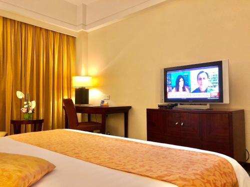 a hotel room with a bed and a flat screen tv at Ningbo Portman Plaza Hotel in Ningbo