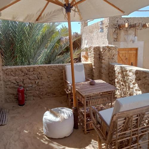 a patio with a table and chairs and an umbrella at Tanirt ecolodge in Siwa