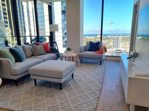 a living room with couches and chairs and windows at Southbank Bay Views Free parking WIFI smart TV in Melbourne