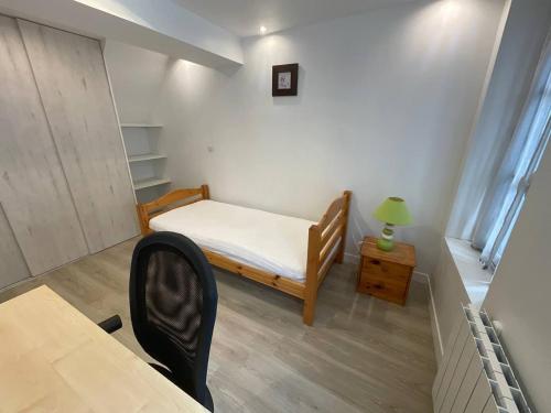 une petite chambre avec un lit et un bureau dans l'établissement 8 les maradas bruns, à Pontoise