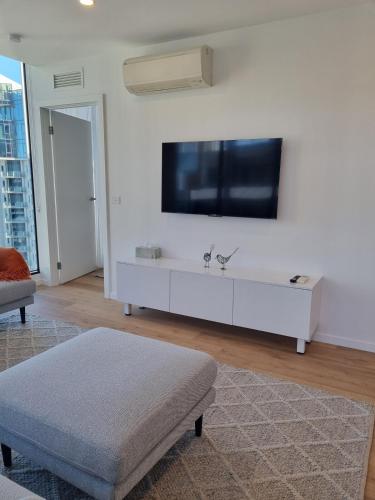 a white living room with a flat screen tv on a wall at Southbank Bay Views Free parking WIFI smart TV in Melbourne