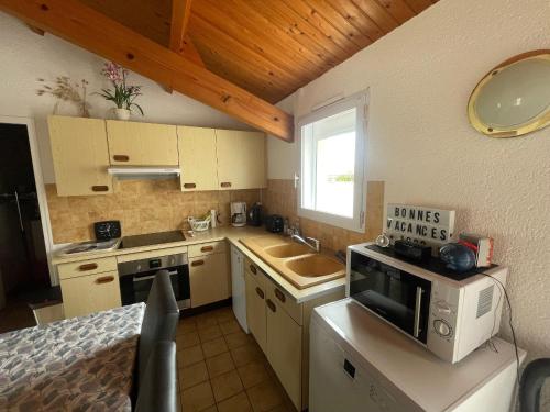 une petite cuisine avec un évier et un micro-ondes dans l'établissement Charmant pavillon avec jardin clos, terrasse, et tout confort, à 950m de la plage des Sables-d'Olonne - FR-1-92-743, à La Pironnière