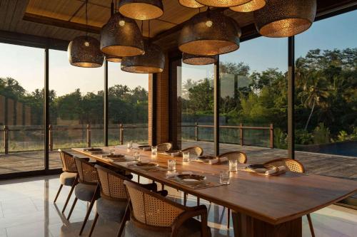 a long table in a room with chairs and windows at Garrya Bianti Yogyakarta in Yogyakarta
