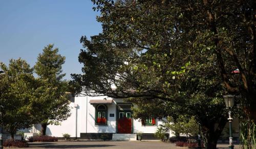 a white building with a red door and trees at Garrya Bianti Yogyakarta in Yogyakarta