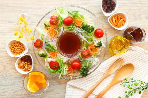 a table with a plate of food with tomatoes and vegetables at Hiyori Hotel Osaka Suminoekoen Station in Osaka