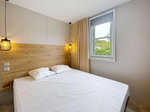 une chambre avec un lit blanc et une fenêtre dans l'établissement Mobil-home de Grand Confort à 200m de la plage avec piscine chauffée, 2 chambres, parking, wifi inclus - FR-1-361A-44, à Jullouville