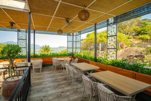 a restaurant with tables and chairs and large windows at Green Oasis Nha Trang Resort in Nha Trang