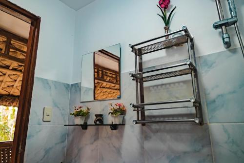 a bathroom with a mirror and a shelf with flowers at TANGLAW - A Private Rest house with pool near Tagaytay City in Alfonso