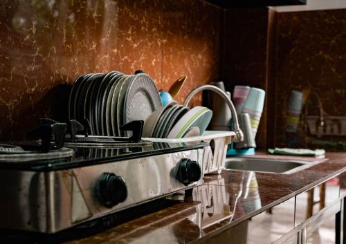 a kitchen counter with plates on a stove and a sink at TANGLAW - A Private Rest house with pool near Tagaytay City in Alfonso